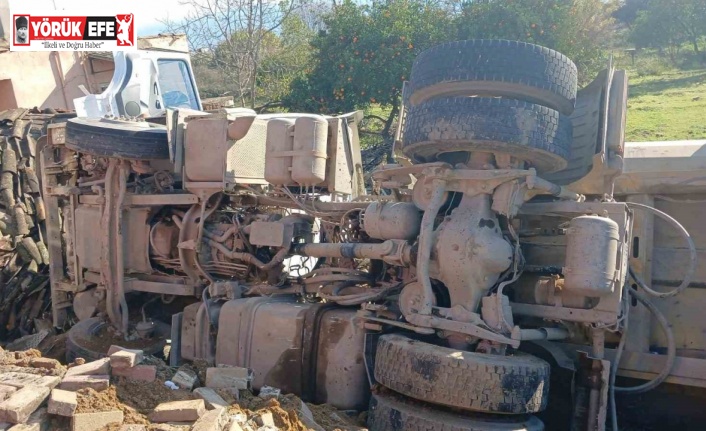 Otobüse çarpan kum yüklü kamyon, bir evin  bahçesine devrildi
